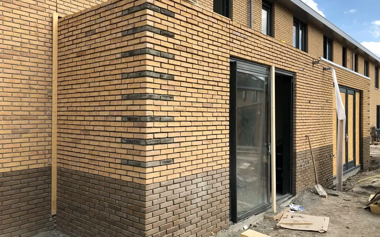 Rij nieuwbouwwoningen in aanbouw met donkere kozijnen en een pui in de achtergevel